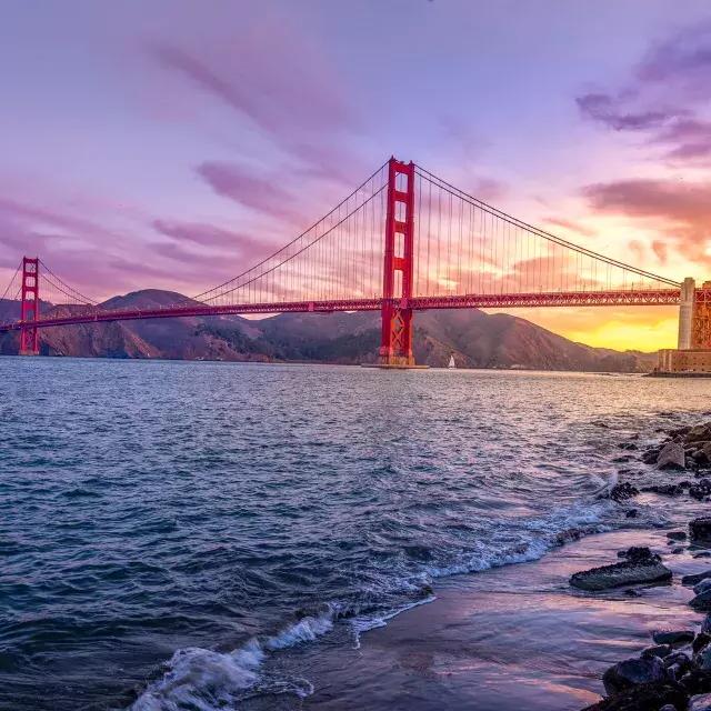 的 金门大桥 at sunset with a multicolored sky 和 的 San Francisco Bay in 的 foreground.